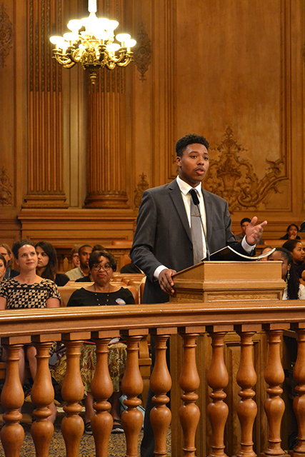 a young african american man in a suit stands at a podium